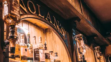 Mehrere Whiskyflaschen auf Holztresen ausgestellt.