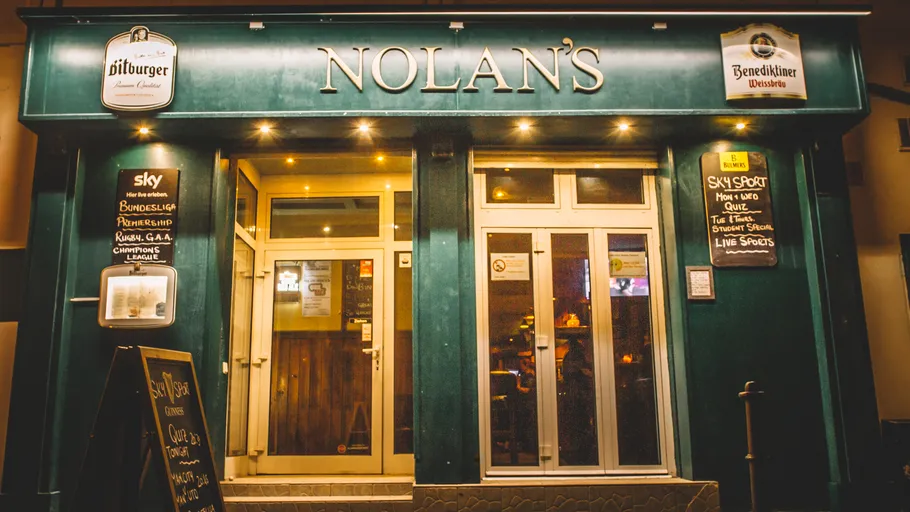 Pub entrance with illuminated signage at night.