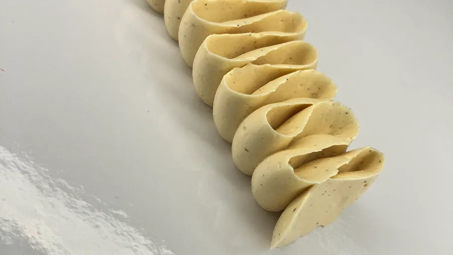 Folded pasta dough on white surface.
