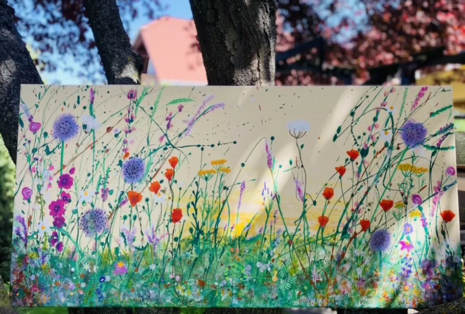 Colorful floral painting against tree and sky.