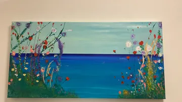 Colorful flowers painted in front of blue sea.