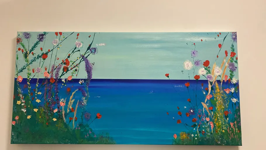Bunte Blumen gemalt vor blauem Meer.