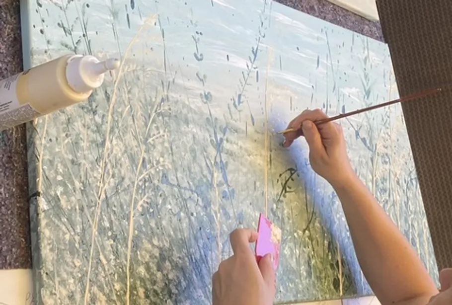 Hands painting abstract landscape on canvas.