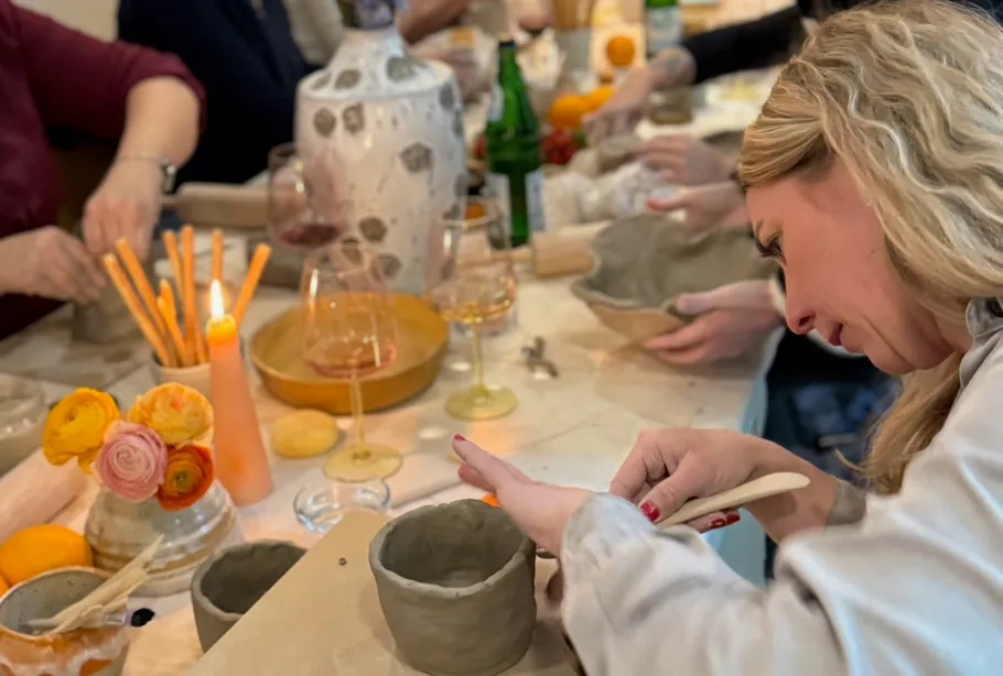 People creating pottery at a table gathering.