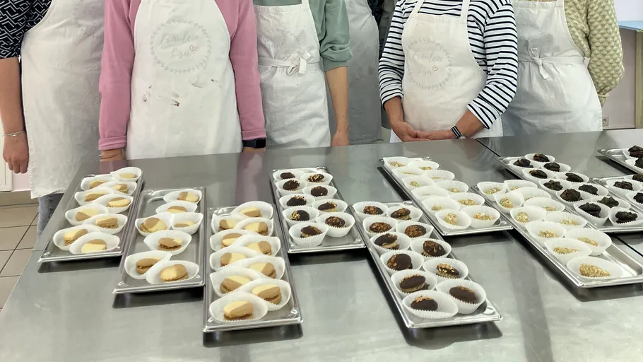 Personen stehen hinter Tabletts mit Keksen.