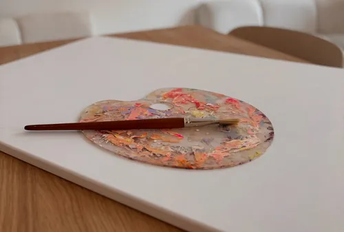 Pinsel ruht auf bunter Palette.