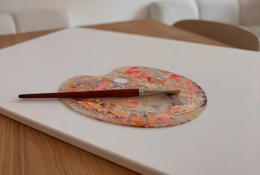 Pinsel ruht auf bunter Palette.