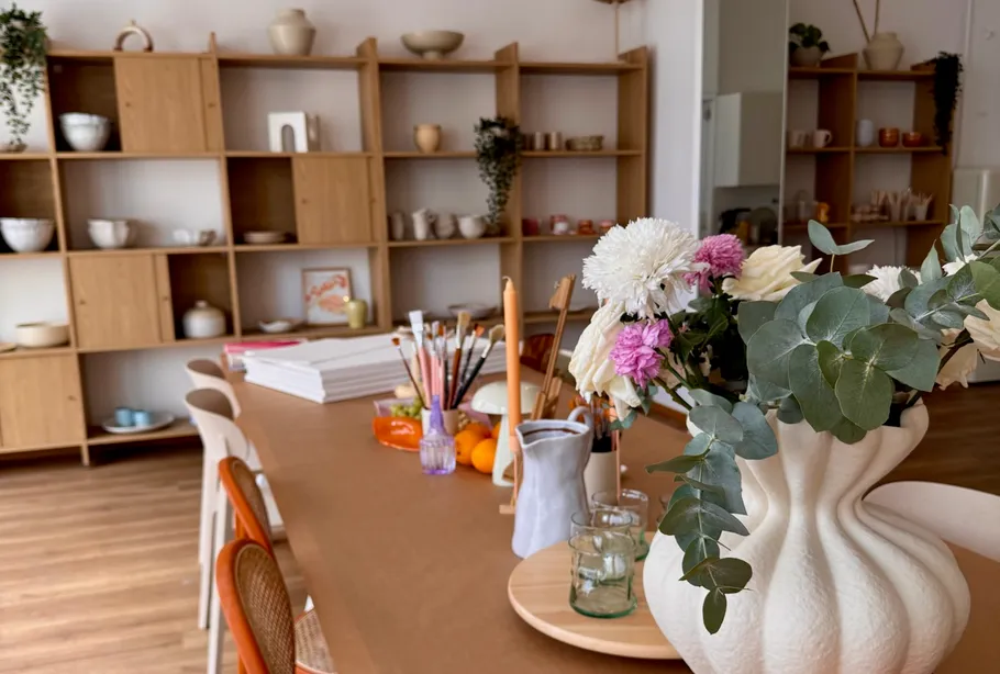 Blumen auf Tisch im Kunststudio, Regale im Hintergrund.
