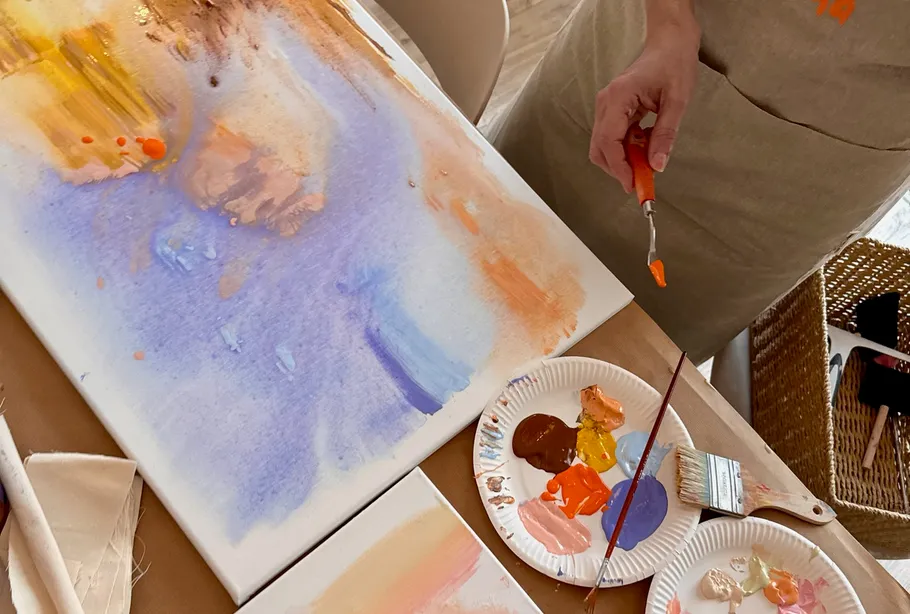 Person painting abstract art on a canvas.