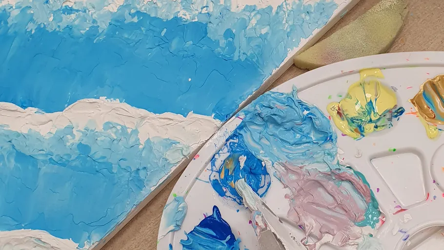 Malutensilien und Leinwand mit blauen Wellen.