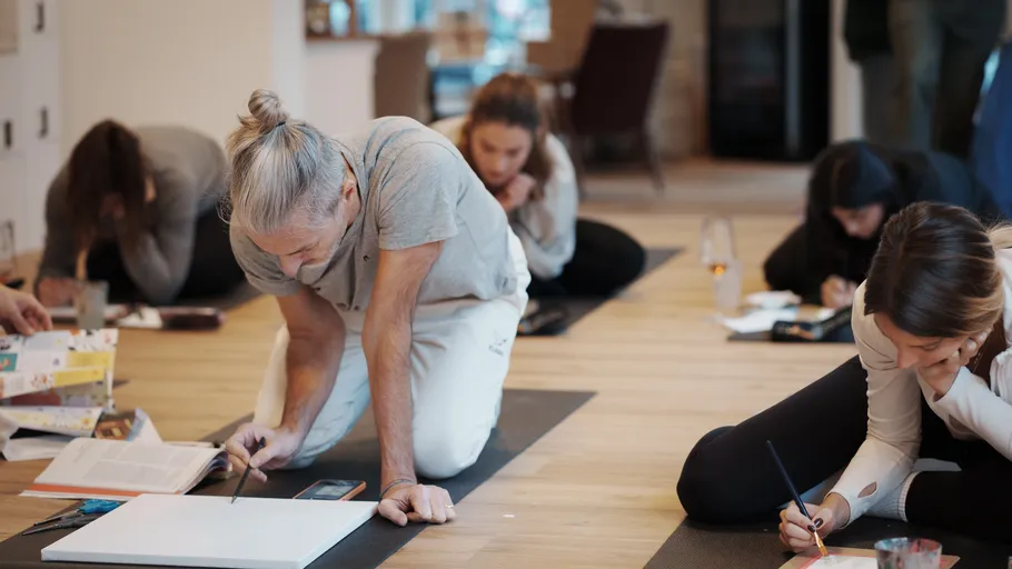 People kneeling, creating art in a studio.