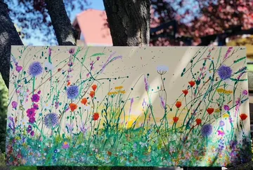 Vibrant wildflower painting displayed outdoors.