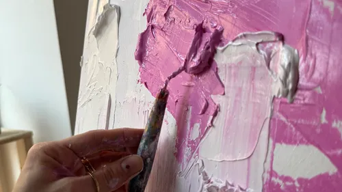 Hand painting on canvas with pink paint.