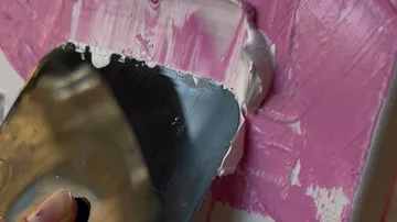 Malmesser verteilt Farbe auf Leinwand.