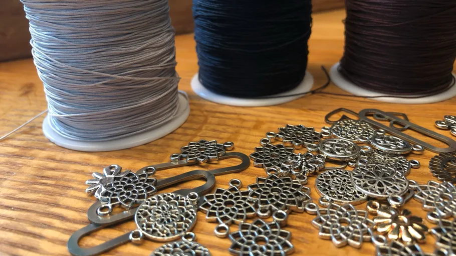 Garnspulen und Metallanhänger auf Tisch.