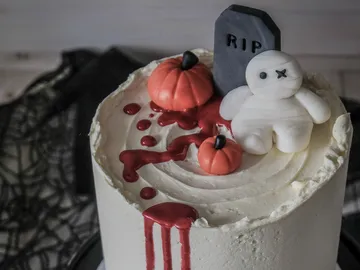Torte mit Halloween-Dekoration, blutige Sauce und Kürbisse.