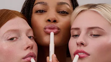 Three people applying lip balm together.