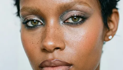 Woman with glittery eye makeup, serious expression.