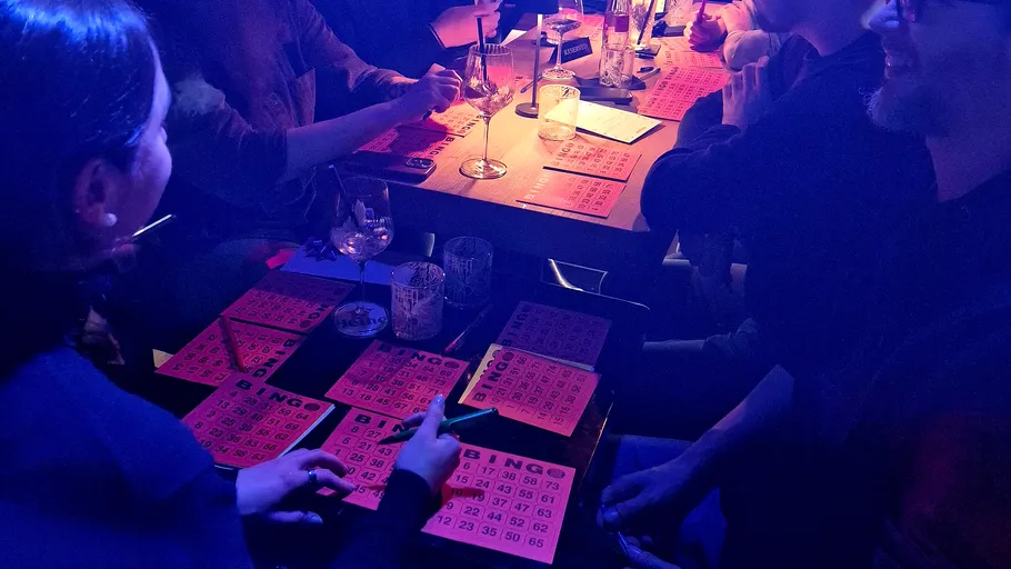 Personen spielen Bingo an einem abgedunkelten Tisch.