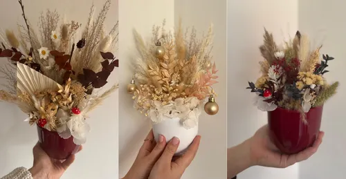 Hand hält Töpfe mit Trockenblumen-Arrangements.