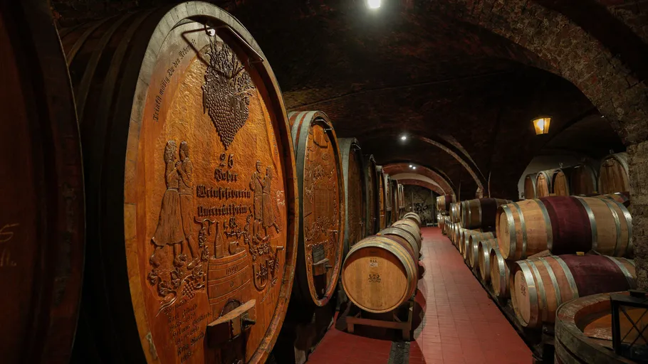 Große Holzfässer in einem schwach beleuchteten Keller.