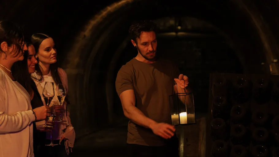 Man holding lantern in wine cellar.