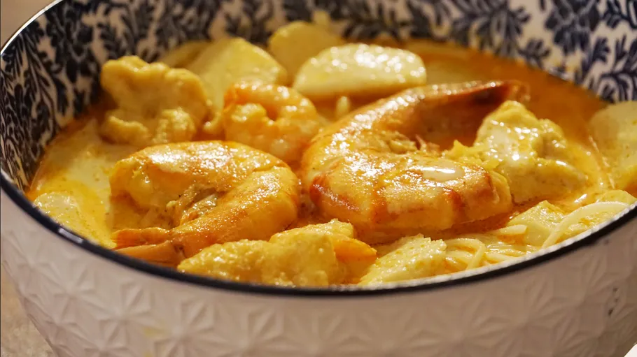 Bowl of shrimp and noodles in curry sauce.