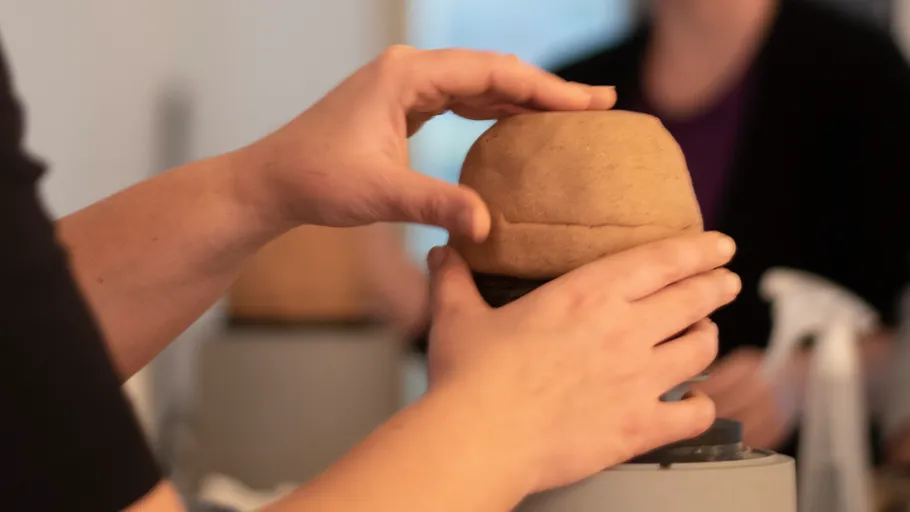 Hands shaping dough in a kitchen setting.