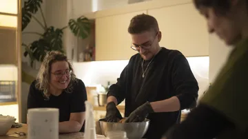 People cooking and smiling in kitchen.