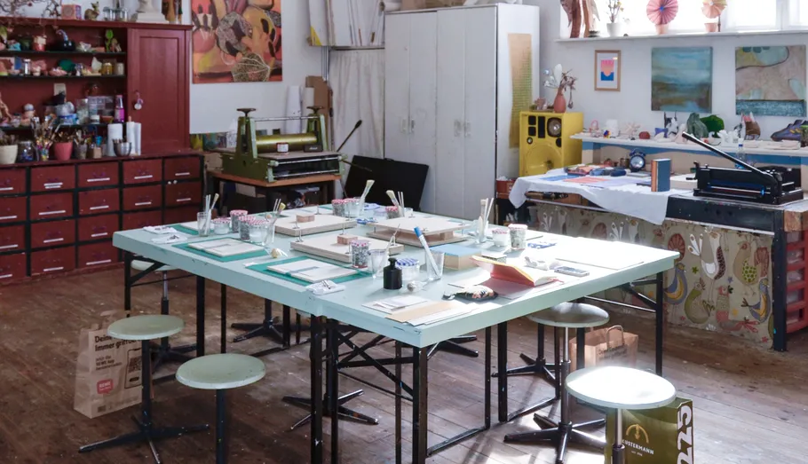 Kunststudio mit Tischen und Kunstmaterialien.