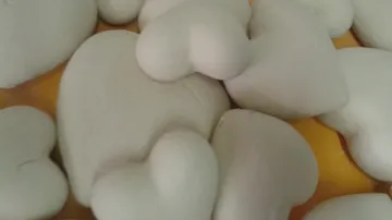 Haufen herzförmiger Steine auf Tisch.