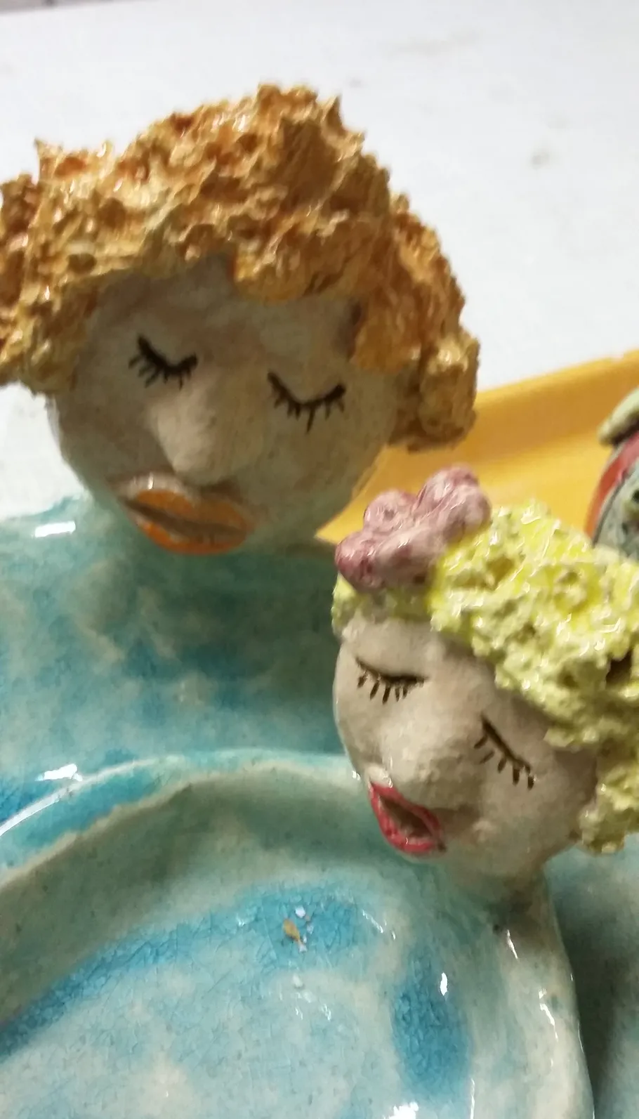 Keramikfiguren mit geschlossenen Augen auf blauem Hintergrund.