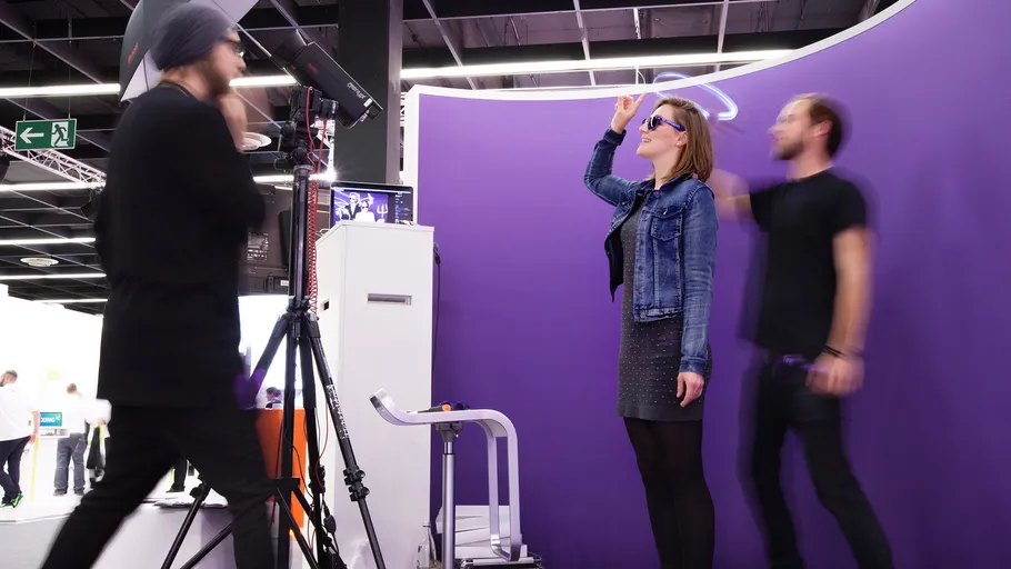 Woman poses with neon artwork at exhibition.