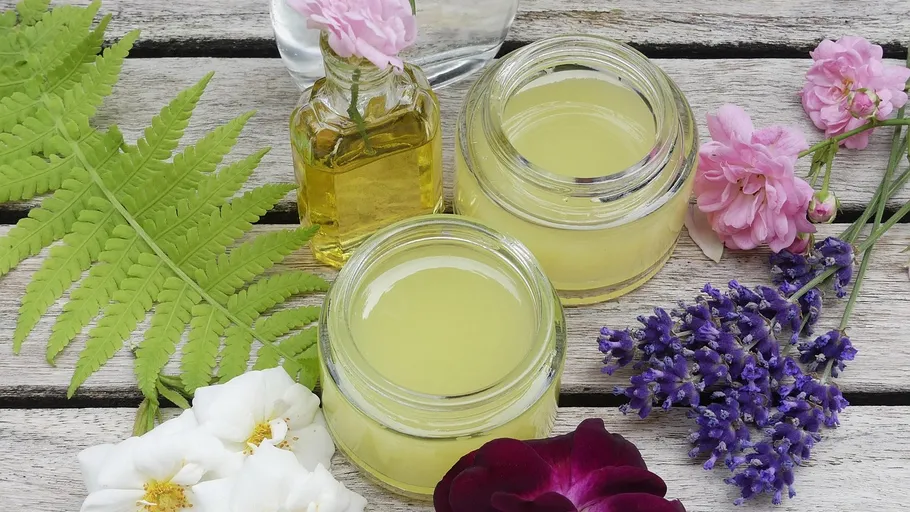 Jars with oil and flowers on wood.