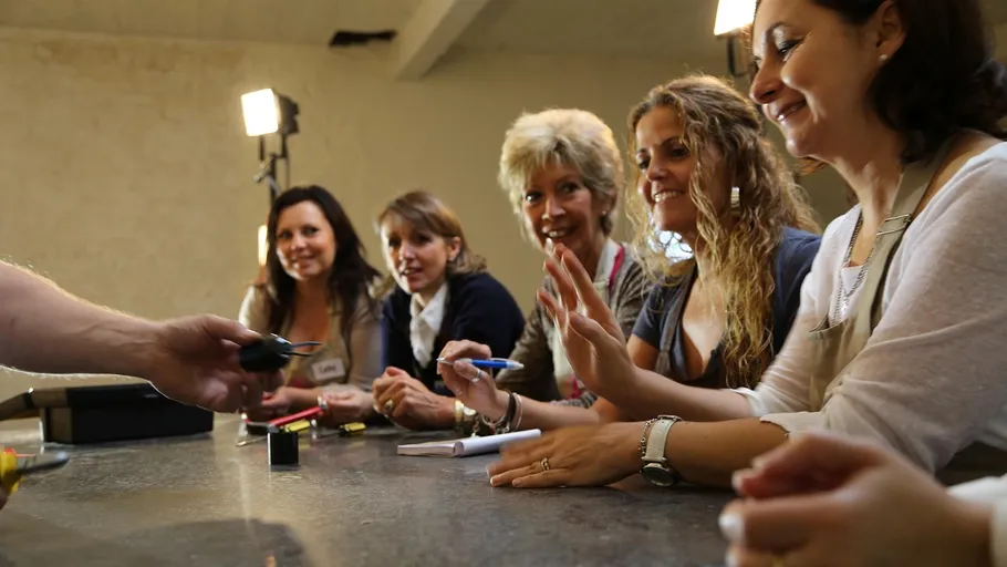 Five women sitting, smiling, receiving feedback inside room.