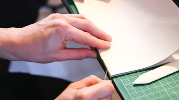 Hands sewing paper bookbinding process.
