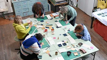 Five people crafting around a large table.