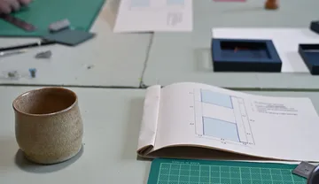 Open book and mug on a desk.