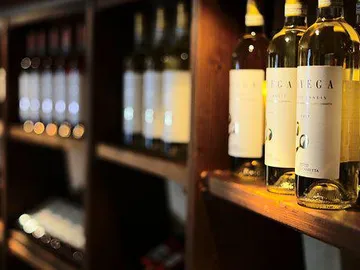 Wine bottles are on a wooden rack in the background.