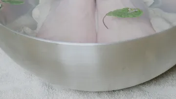 Füße in einer Metallschüssel mit Blättern einweichen.