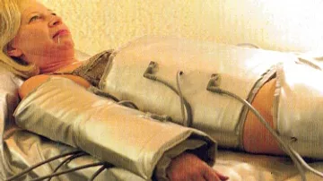 Person im Massagesuit liegt auf Bett.