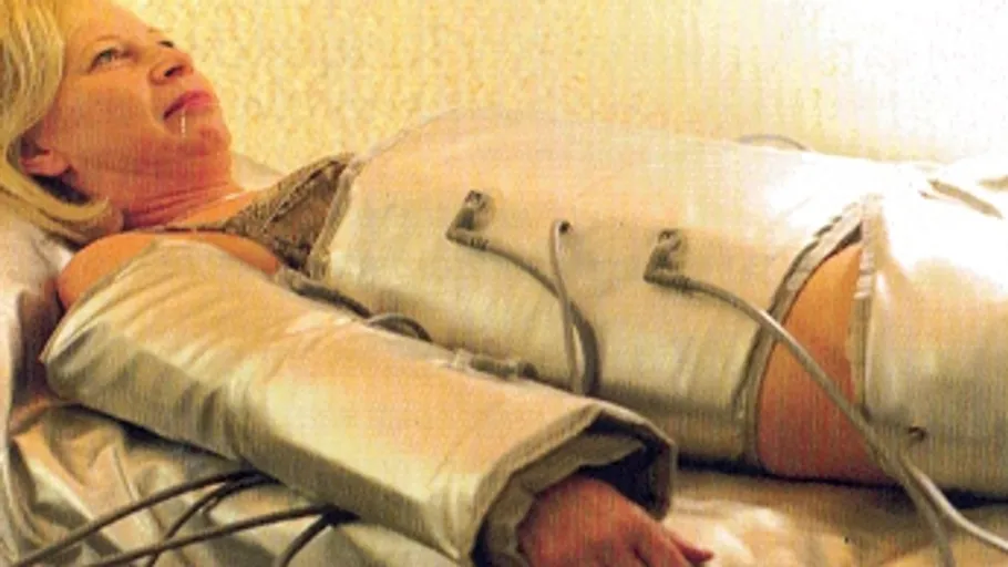 Person in massage suit lying on bed.