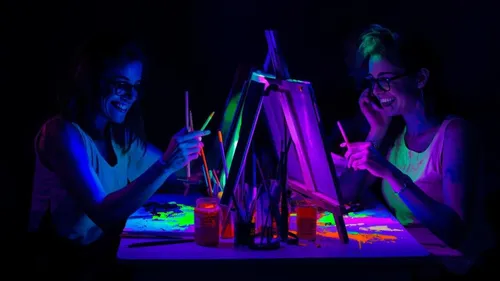 Zwei Personen malen unter Schwarzlicht.