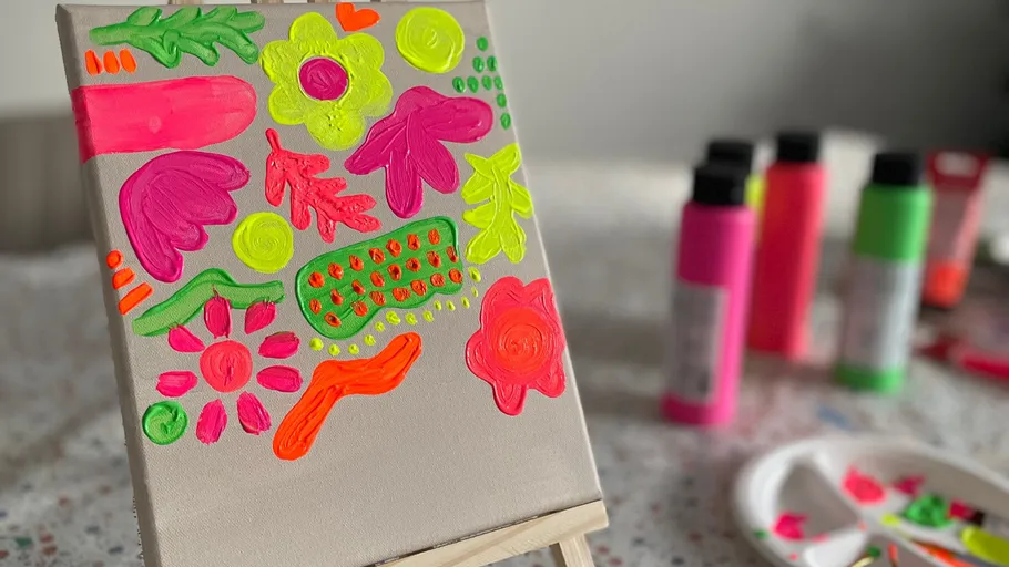 Colorful abstract painting on canvas with paint bottles.