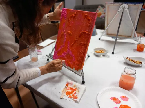 Person painting on canvas with textured paint.