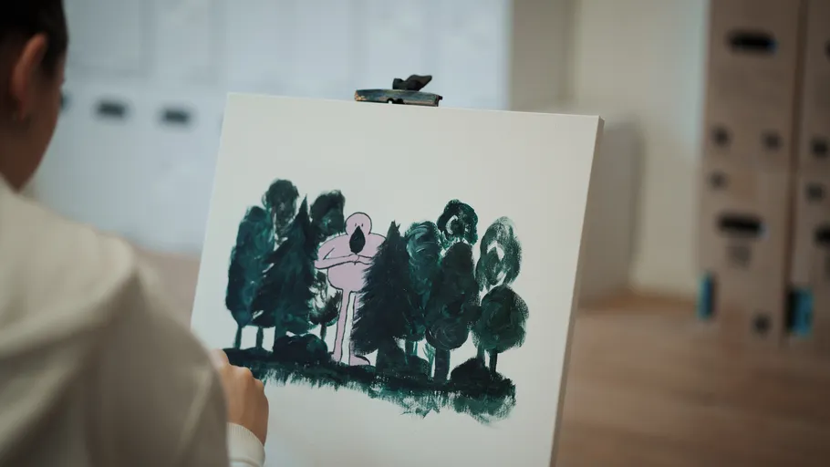 Person painting a forest scene on canvas.