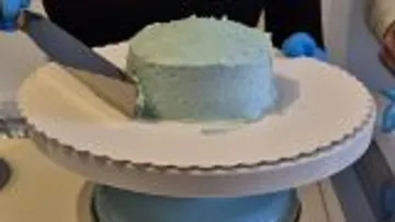 Cake being frosted on turntable.