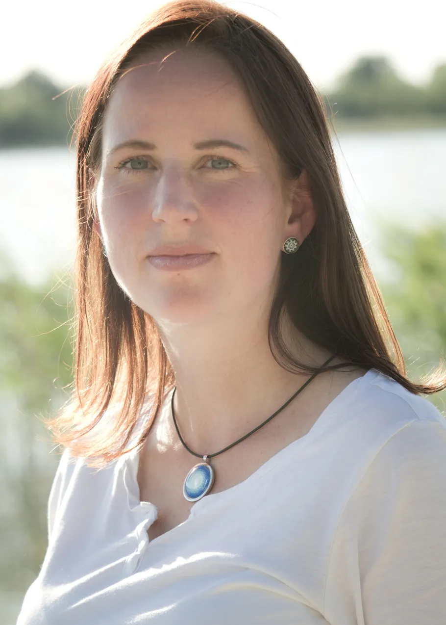 Frau mit Halskette, draußen am Wasser.