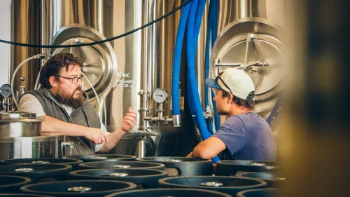 Two men talking in a brewery.