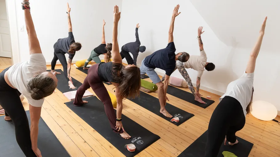 Menschen machen Yoga in einem Kursraum.